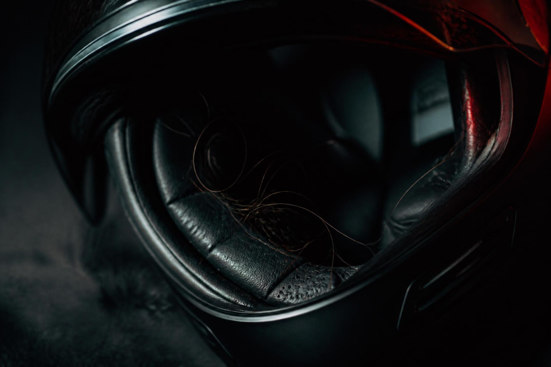 Close-up of a dark motorcycle helmet interior with loose hair strands caught in the padding